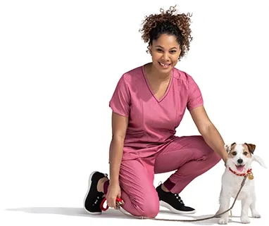 A kneeling woman in a pink outfit pets her terrier